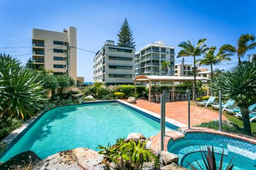 - une piscine bordée de palmiers et de bâtiments dans l'établissement Surfers Beachside Holiday Apartments, à Gold Coast