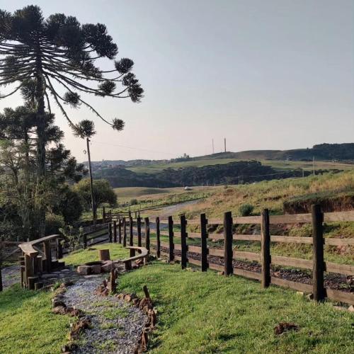 a wooden fence with benches in a field at Pousada Emerich in Cambara do Sul