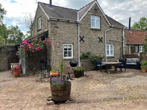 an old stone house with flowers in front of it at The Bothy at Oak Farm in Usk