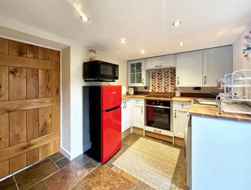 a kitchen with a red refrigerator and a microwave at Wren Cottage North Norfolk in Hindringham