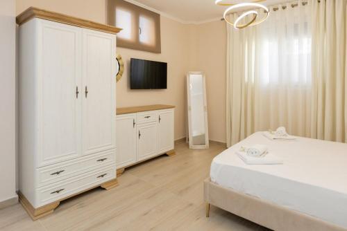 a bedroom with a white bed and a large white cabinet at Valery Apartments in Pefkohori