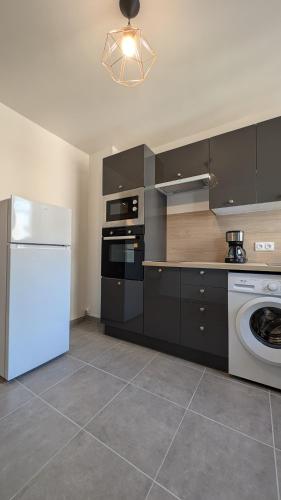 La cuisine est équipée d'un réfrigérateur blanc et d'un lave-vaisselle. dans l'établissement le Cocon de Gap - centre-ville, à Gap