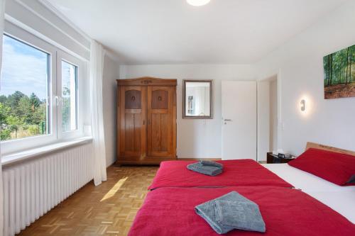 a bedroom with a bed with red sheets and a window at Familie Quednow - Im Algi in Görwihl