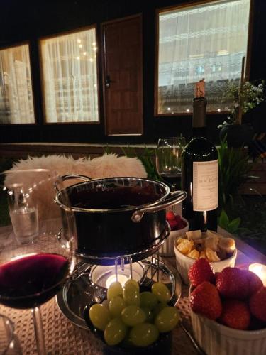 a table with a bunch of fruit and a bottle of wine at Colina Branca in Rio Rufino