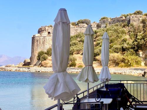 three white umbrellas sitting on a dock near the water at Xenios Zeus Rooms in Koroni