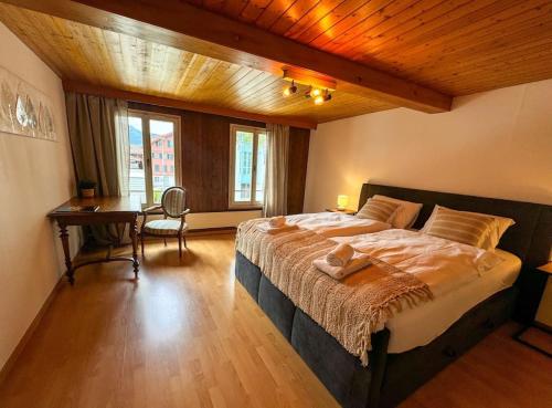 a bedroom with a large bed and a desk at City Center View Apartment in Interlaken