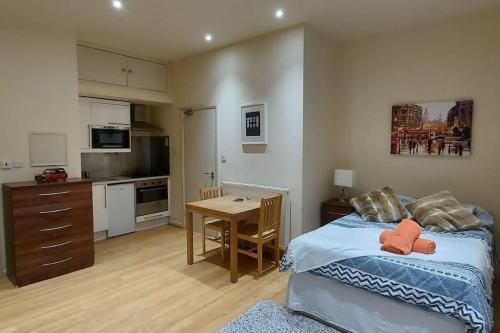 a bedroom with a bed and a table and a kitchen at Studio 47B in London