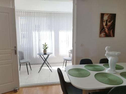 une salle à manger avec une table et des chaises blanches dans l'établissement Au calme et proche de tout !, à Perpignan