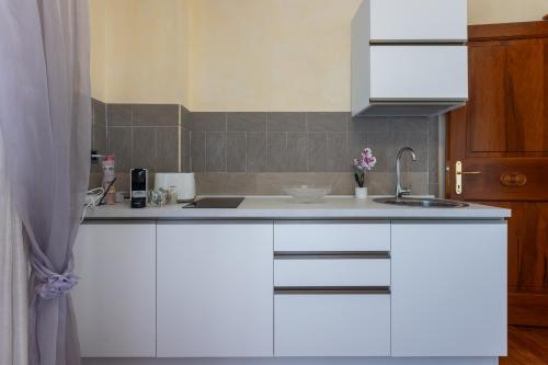 una cucina con mobili bianchi e un lavandino di La Casa di Tonina a Quartu SantʼElena