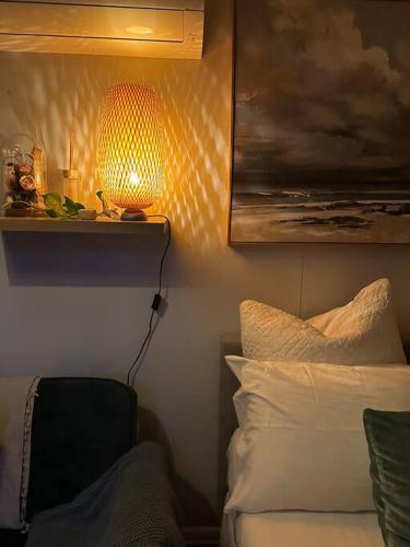a bedroom with a bed and a lamp on the wall at Tiny Home Beach Serenity! in Sydney