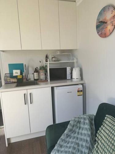a kitchen with white cabinets and a microwave at Tiny Home Beach Serenity! in Sydney
