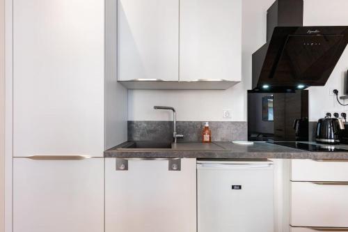 une cuisine avec des armoires blanches et un évier dans l'établissement AU GOÛT DU JOUR T2 Climatisé, à Toulouse
