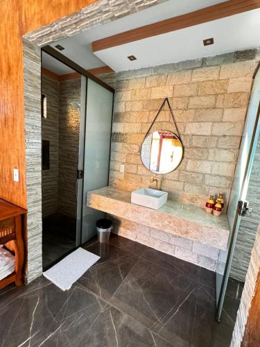 a bathroom with a stone wall and a mirror at Pousada Raio de Luz in Pirenópolis