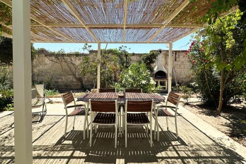 a patio with a table and chairs under a pergola at Villa Layla on the beach in Torre Lapillo