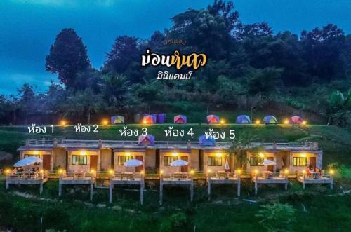 a building with tables and umbrellas at night at ม่อนหนาว ลานกางเต็นท์ in Mon Jam
