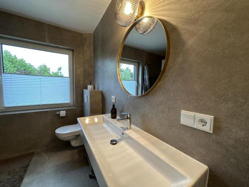 Un baño con lavabo, espejo e inodoro. en geschmackvolle Wohnung in Katsdorf, modern und bequem, en Katsdorf