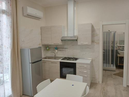 a kitchen with white appliances and a white table and chairs at Butterfly Apartments in Palermo