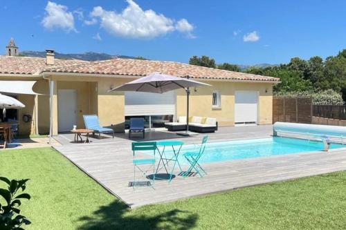 une piscine avec des chaises et un parasol à côté d'une maison dans l'établissement Villa Paesolu piscine chauffée charme et sérénité, à Porto-Vecchio