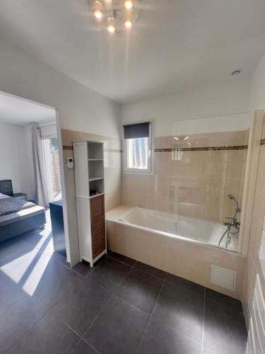 - une salle de bains blanche avec baignoire et une chambre dans l'établissement Villa Paesolu piscine chauffée charme et sérénité, à Porto-Vecchio