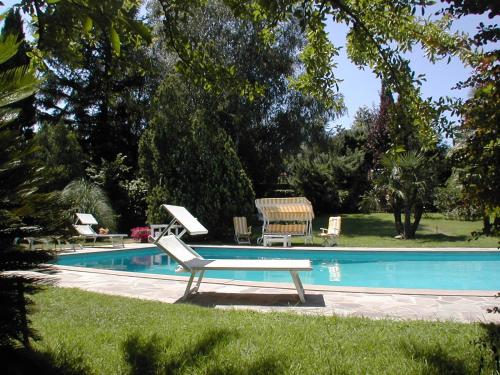 a swimming pool with two lawn chairs and a bench at Hotel Villa Clementina in Bracciano