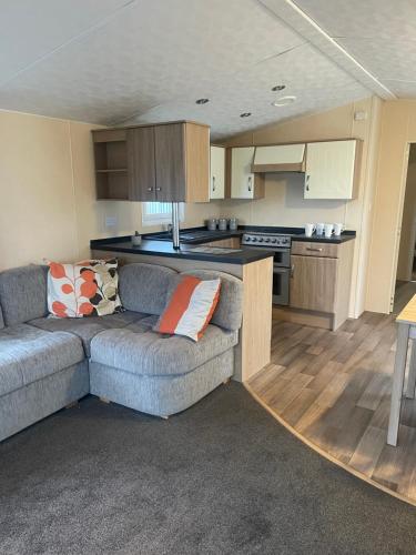 a living room with a couch and a kitchen at Whitehouse Leisure Park N&V Caravan Hire in Kinmel Bay