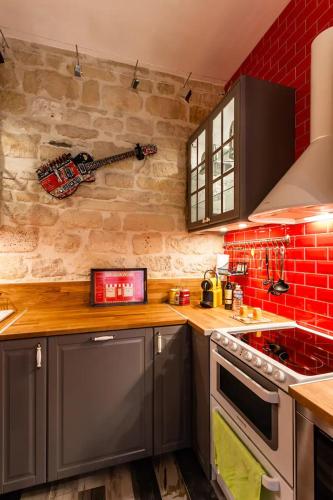 une cuisine avec des placards gris et un mur en briques rouges dans l'établissement Lavie Maison Montmartre Cozy Studio, à Paris