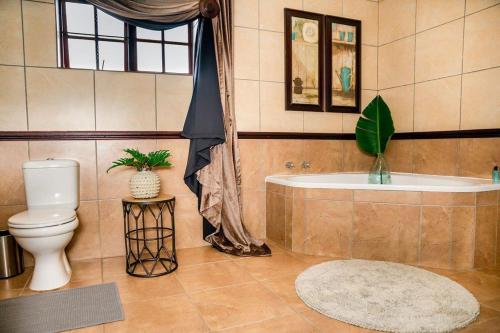 a bathroom with a toilet and a bath tub at Aloe room in Rustenburg