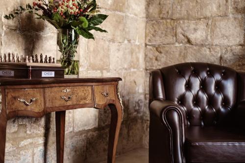 a leather chair next to a desk with a vase of flowers at Palazzo Castagna Boutique Hotel in Hal Ghaxiak