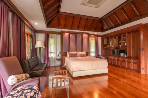 a bedroom with a bed and a couch and a chair at Guru Resort Chiang Mai in Ban Muang Ha