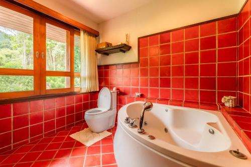 a red tiled bathroom with a tub and a toilet at Guru Resort Chiang Mai in Ban Muang Ha
