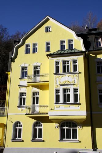 a yellow building with white windows on the side of it at Hotel Vera in Jáchymov