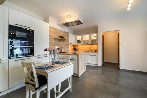 a kitchen with white cabinets and a table with chairs at Aranyhíd Apartman in Balatonföldvár
