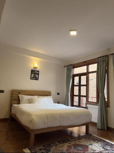 a bedroom with a large bed and a window at Karuna Hotel Patan Kathmandu in Pātan