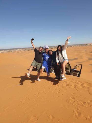 a group of people posing for a picture in the desert at Aladdin merzouga camp in Merzouga