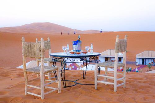 a table and two chairs in the desert at Aladdin merzouga camp in Merzouga