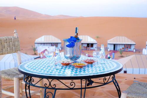 a table with glasses and a bottle of wine at Aladdin merzouga camp in Merzouga
