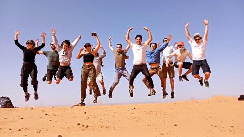 a group of people jumping in the sand at Aladdin merzouga camp in Merzouga