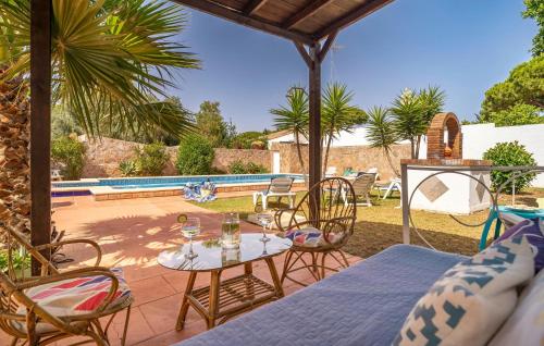 eine Terrasse mit Tisch und Stühlen und einem Pool in der Unterkunft Awesome Home In Chiclana De La Fronter in Chiclana de la Frontera