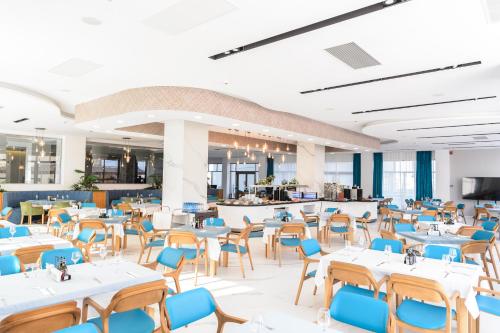 a dining room with white tables and blue chairs at Mirage Beach Spa Hotel in Eforie Nord