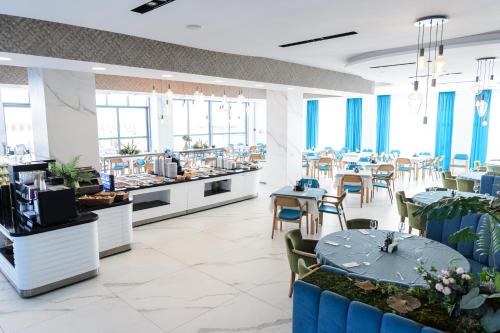 a restaurant with blue tables and chairs and windows at Mirage Beach Spa Hotel in Eforie Nord