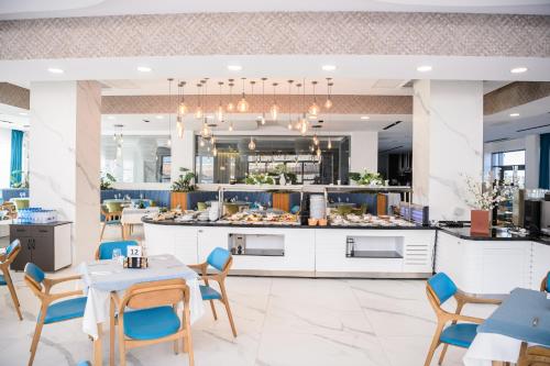 a restaurant with tables and chairs and a kitchen at Mirage Beach Spa Hotel in Eforie Nord