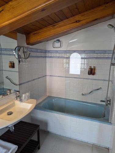 a bathroom with a blue tub and a sink at Hostal de la Plaça - Hotel Boutique in Cabrils