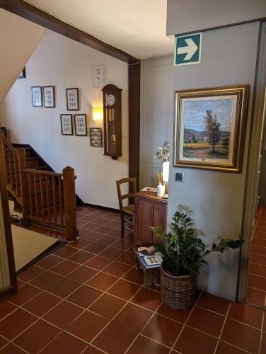 a hallway with a staircase and a clock and a table at Hostal de la Plaça - Hotel Boutique in Cabrils
