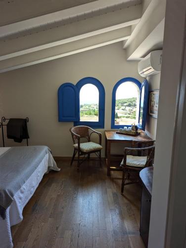 a bedroom with a bed and a table and two windows at Hostal de la Plaça - Hotel Boutique in Cabrils