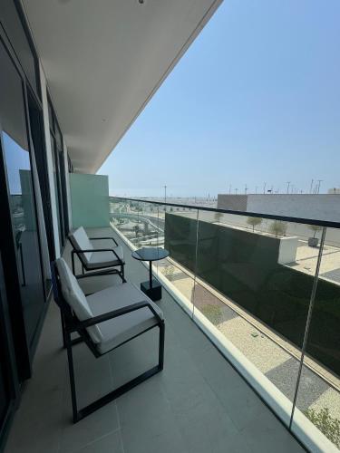 two chairs and a table on the balcony of a building at Address Beach Resort Residence Bahrain in Rayyā