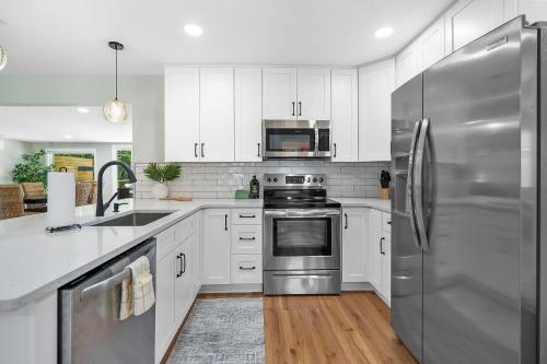 a kitchen with white cabinets and a stainless steel refrigerator at Lakeside Lilypad Wonderland Kayak Grill Firepit in Green Cove Springs