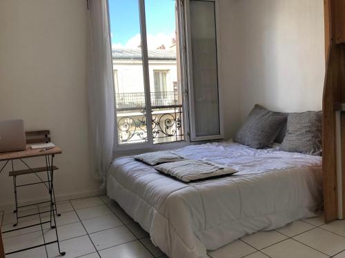 un lit dans une chambre avec une grande fenêtre dans l'établissement Charmant Studio à Belleville, à Paris