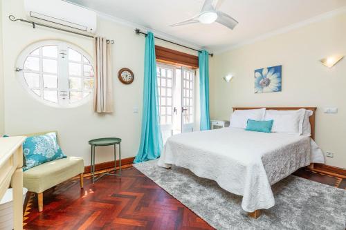 a bedroom with a bed and a chair and a window at Casa Pink Flamingo Spacious Town Centre Villa in Tavira