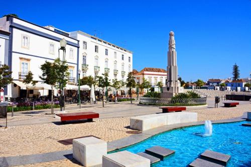 a fountain in a square in a city with buildings at Casa Pink Flamingo Spacious Town Centre Villa in Tavira