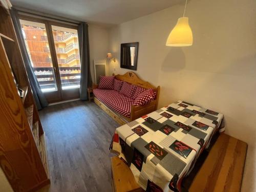 une chambre avec un lit, un canapé et une fenêtre dans l'établissement Appartement skis aux pieds BETELGEUSE, à Risoul